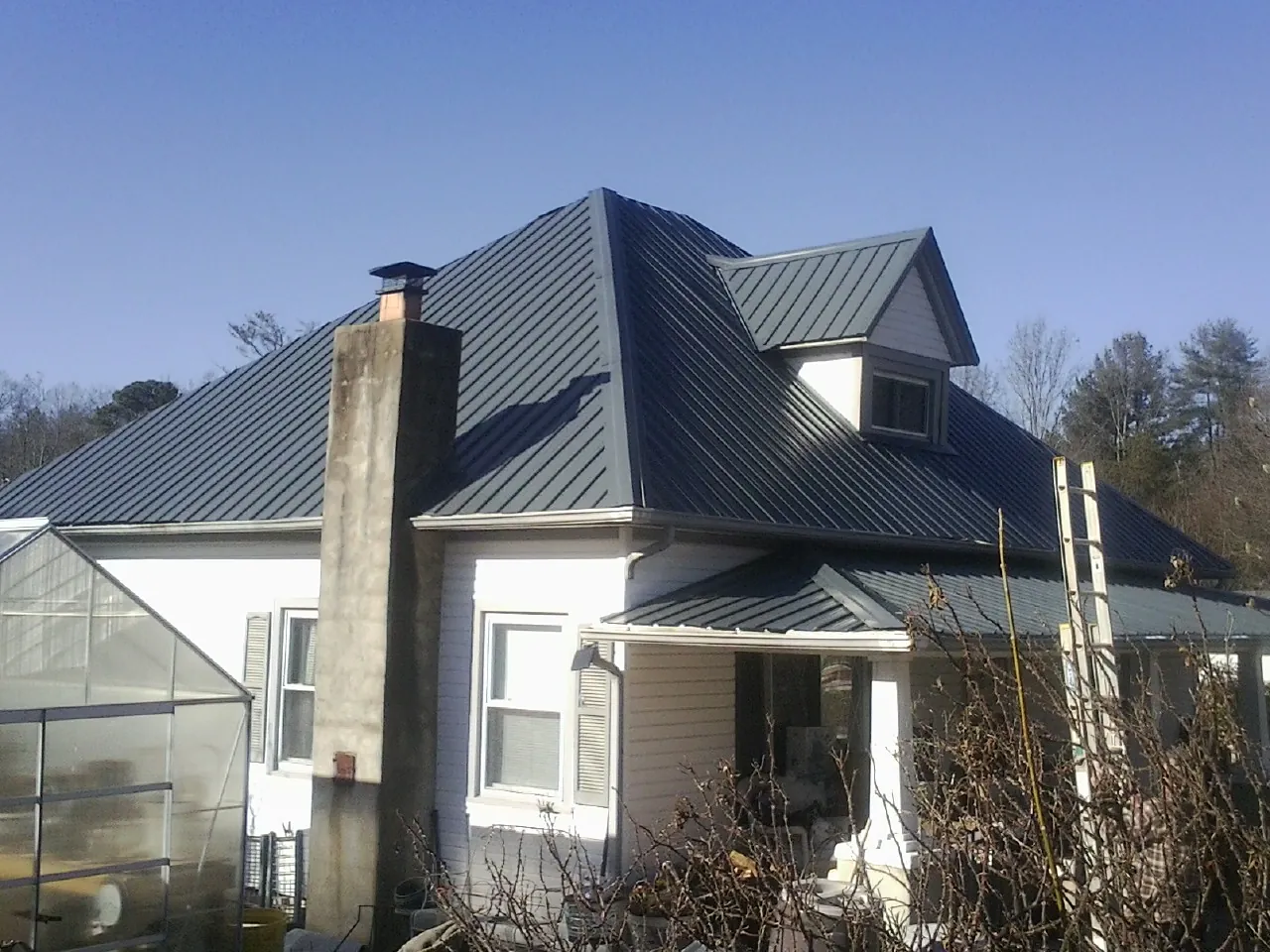 Dark blue standing seam metal roof on a white farmhouse with dormer — Slate & Tile Roof Repair by Roofing Brothers in Wallingford