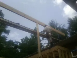 Carpenter setting a ridge beam over a new addition frame — Ice Dam Removal by Roofing Brothers in Wallingford